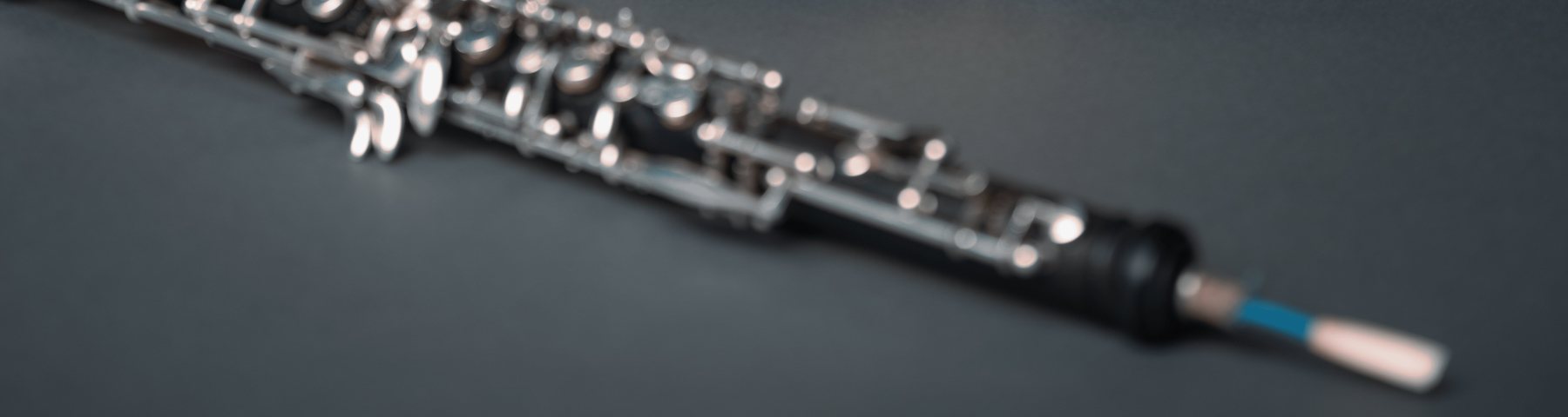 An oboe lying on a table with a reed in place, softly out of focus